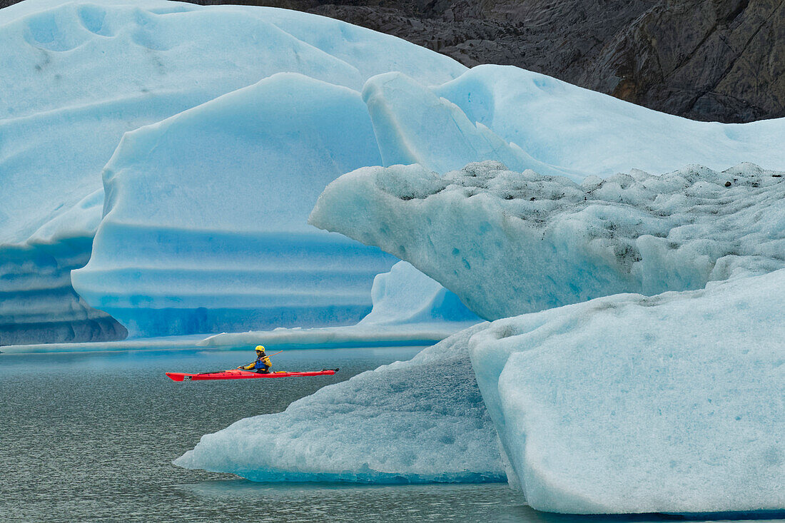 Kayaker exploring Grey Lake amid icebergs, Torres del Paine National Park, Chile, Patagonia