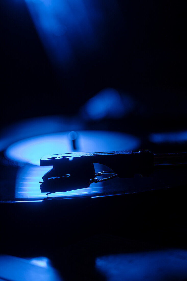 Close-up of a record player needle on record in blue light