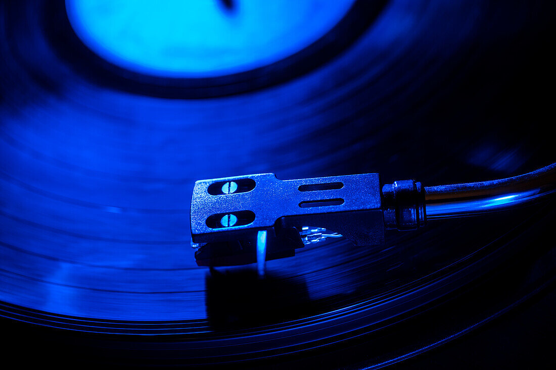 Close-up of a record player needle on record in blue light