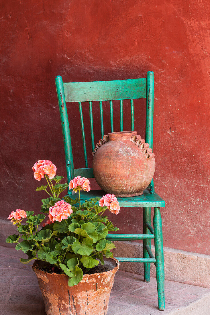 Mexiko, San Miguel de Allende. Geranien, Blumentöpfe und ein Stuhl schmücken einen Eingang.