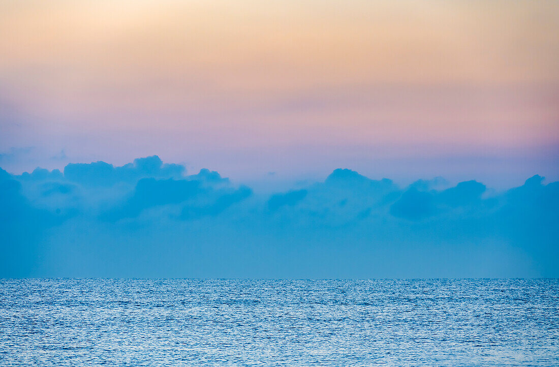 Wolken über ruhigem Meer bei Sonnenaufgang