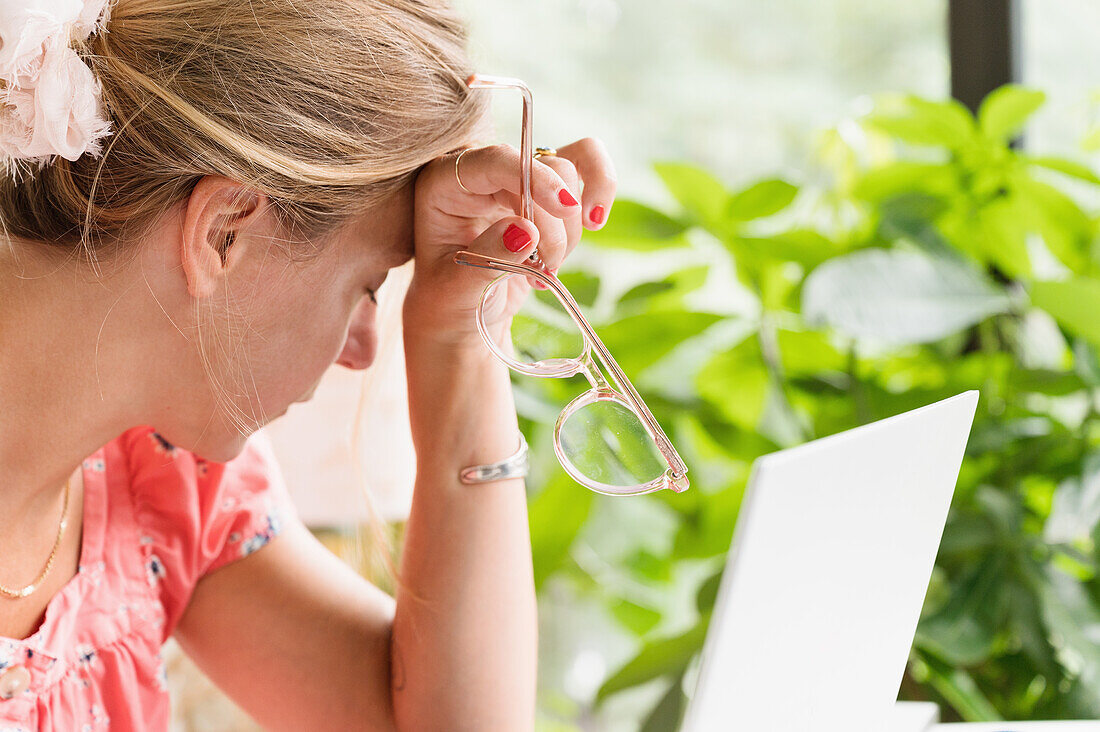 Nahaufnahme einer Frau am Laptop, die den Kopf auf die Hand stützt