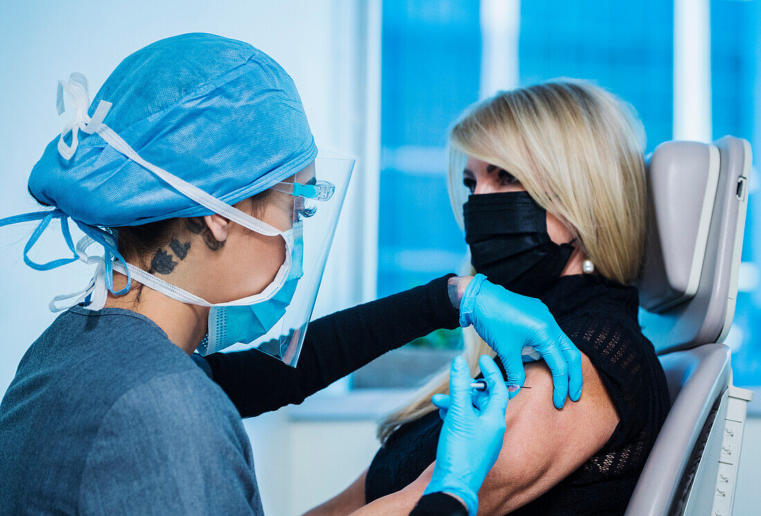 Woman in face mask receiving Covid-19 vaccination
