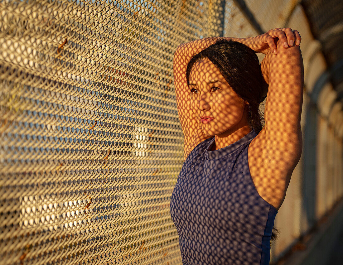 Athlete woman stretching at fence