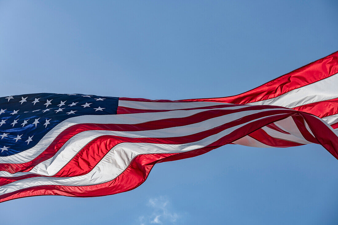 Low angle view of American flag waving in wind against clear sky