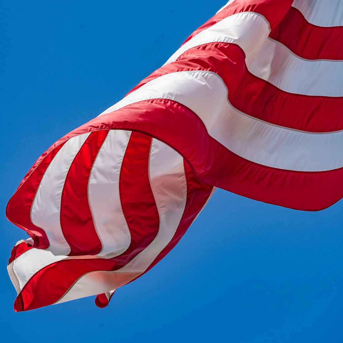 Close-up of American flag waving in wind against clear sky