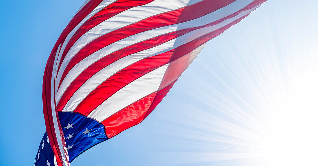 Low-Winkel-Ansicht der amerikanischen Flagge weht im Wind gegen den klaren Himmel mit Sonne