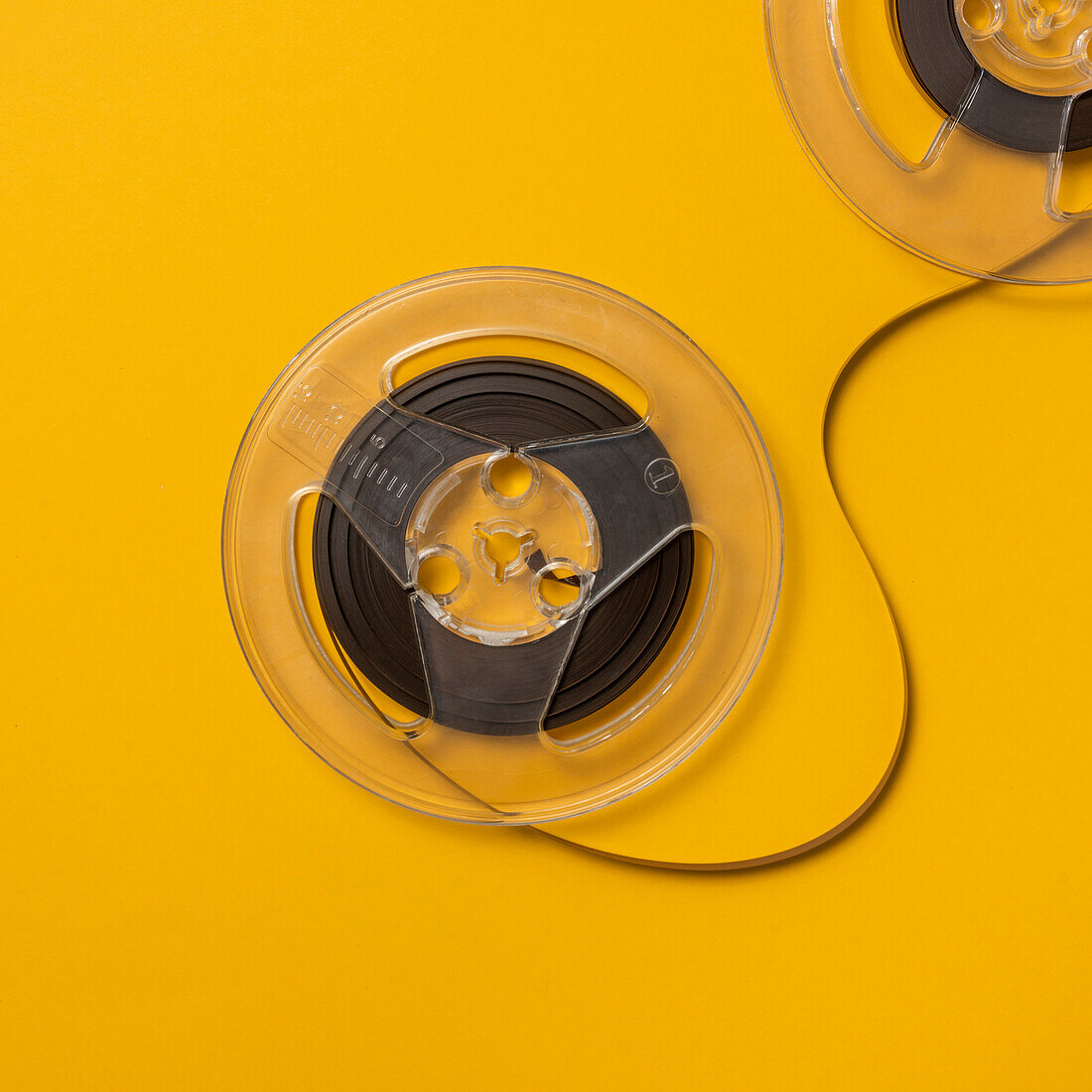 Draufsicht auf Retro-Tonbandspulen vor gelbem Hintergrund