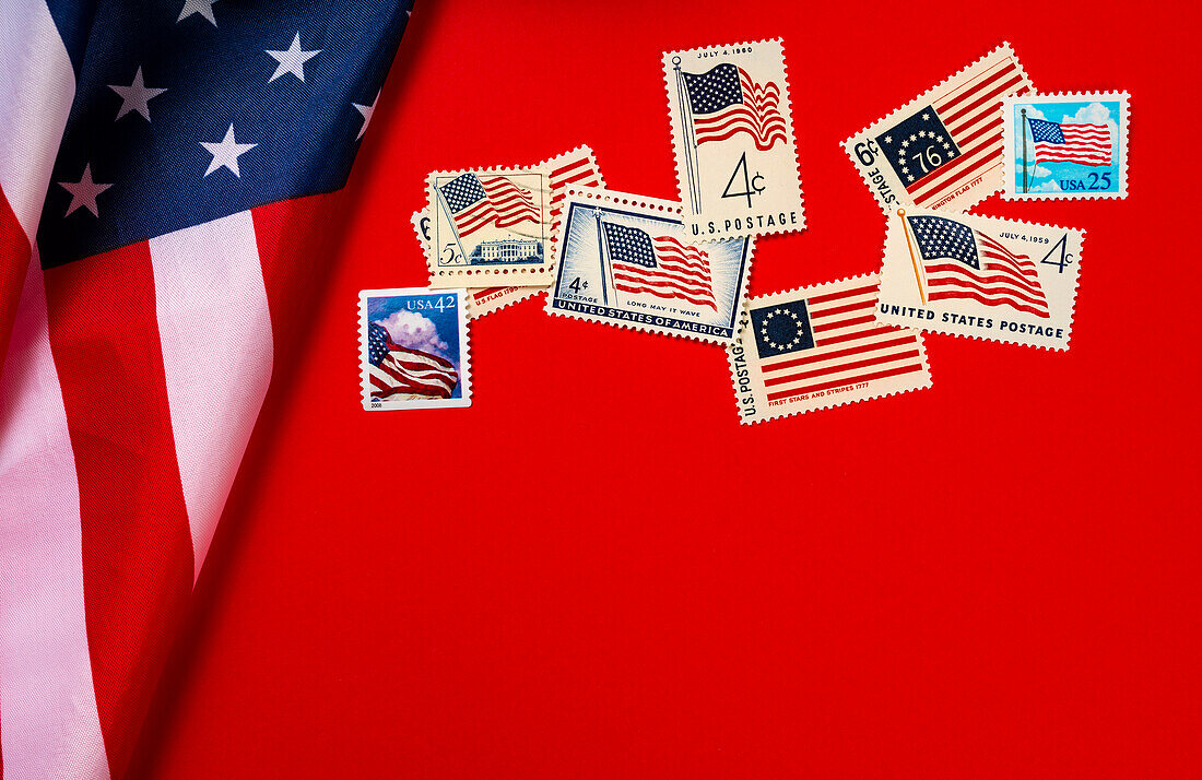 Retro-Briefmarken und amerikanische Flagge vor rotem Hintergrund
