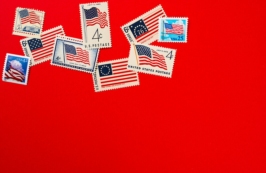 Retro-Briefmarken und amerikanische Flagge vor rotem Hintergrund