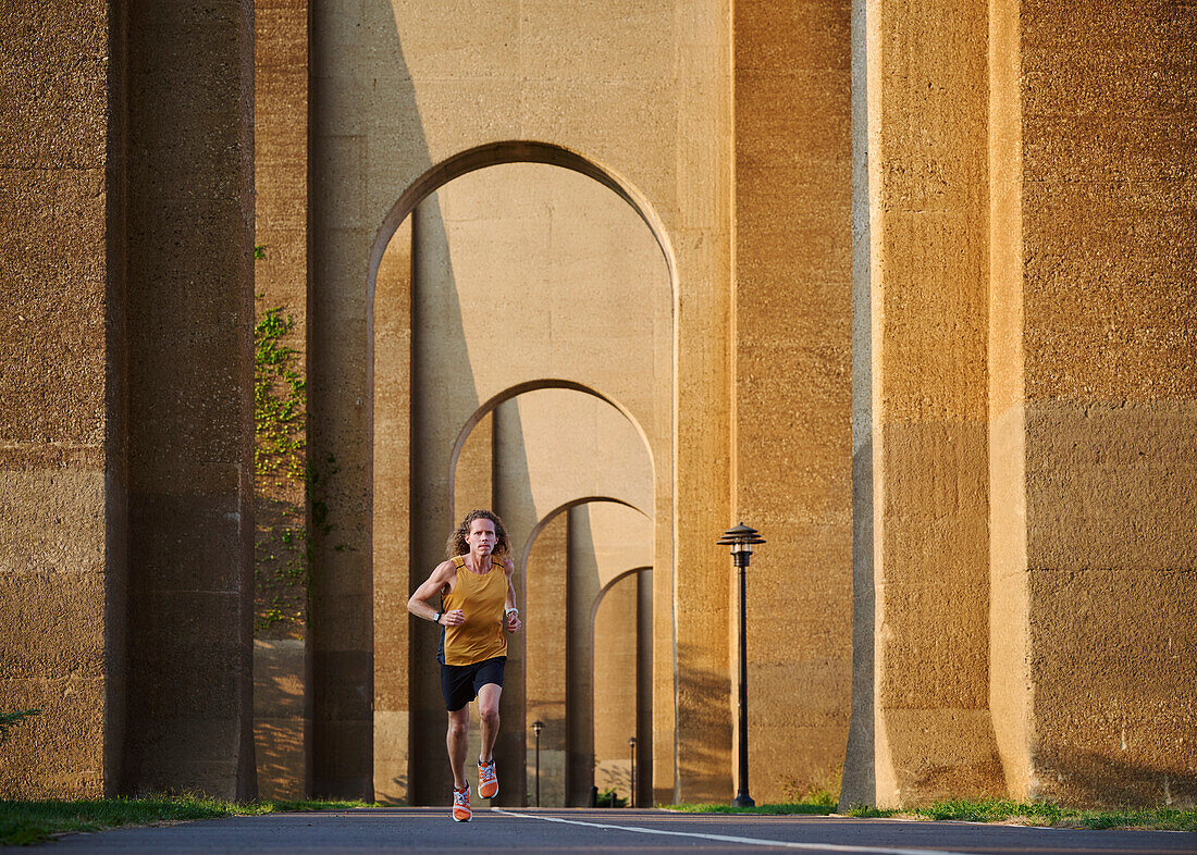 Mann joggt unter einer Brücke