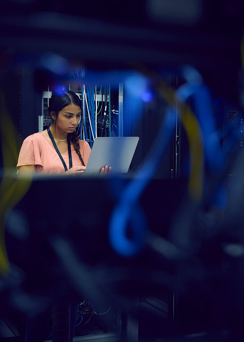 Female technician using laptop in server room