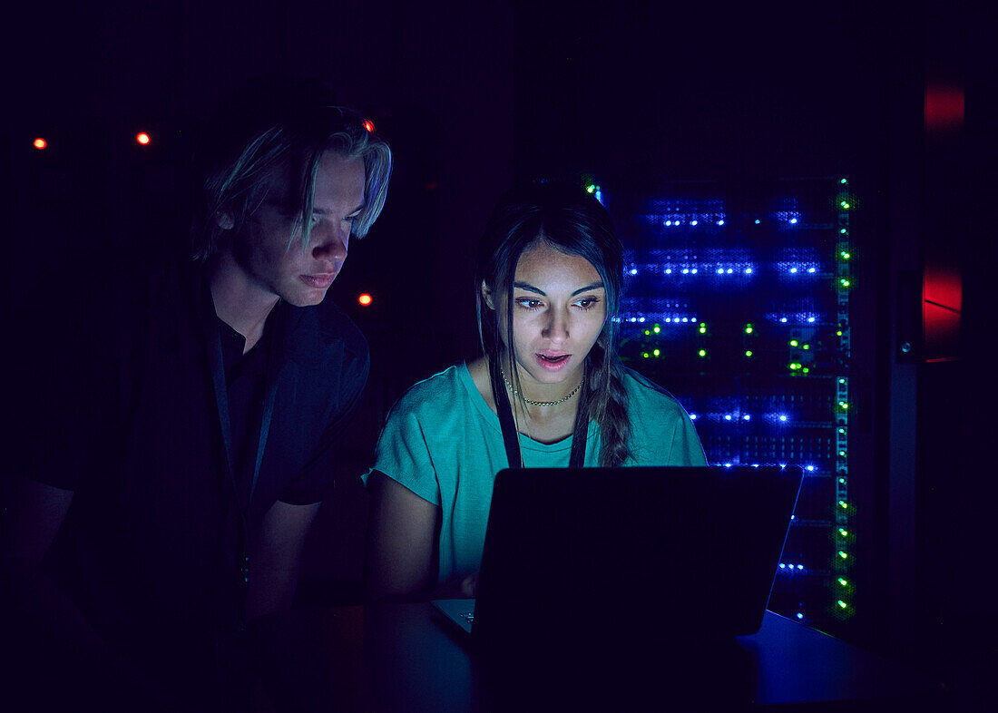 Technicians using laptop in server room