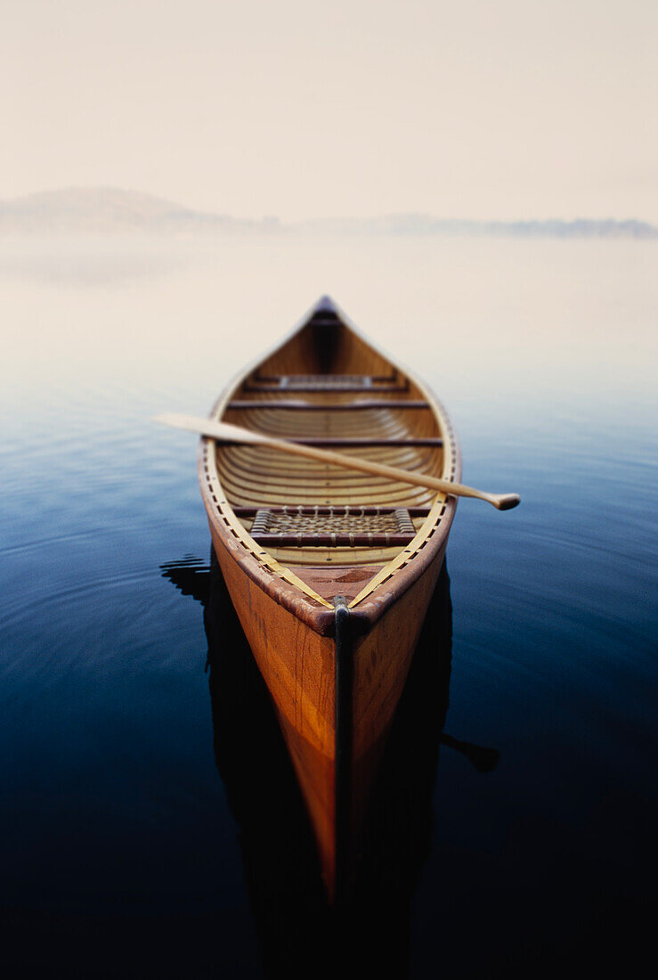 United States, New York, Canoe in morning mist on Lake Placid, Adirondacks State Park