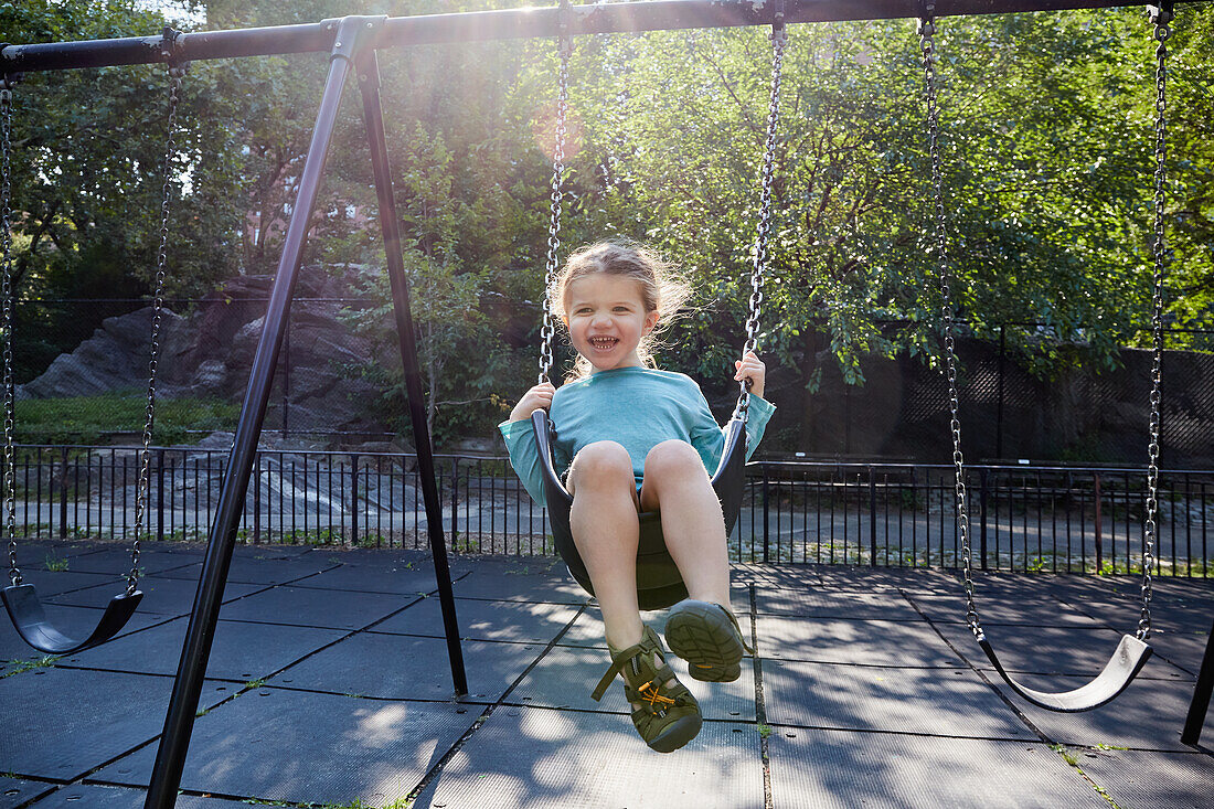 Smiling girl (2-3) on swing in park