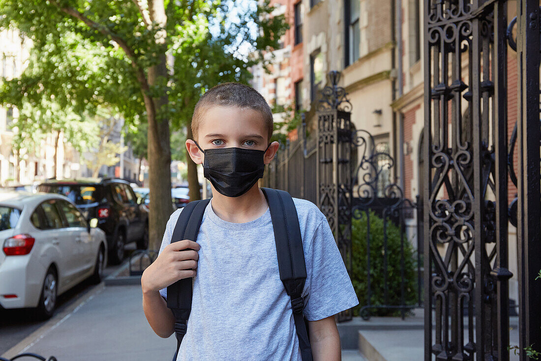 USA, New York, New York City, Porträt eines Jungen (8-9) mit Gesichtsmaske auf dem Gehweg