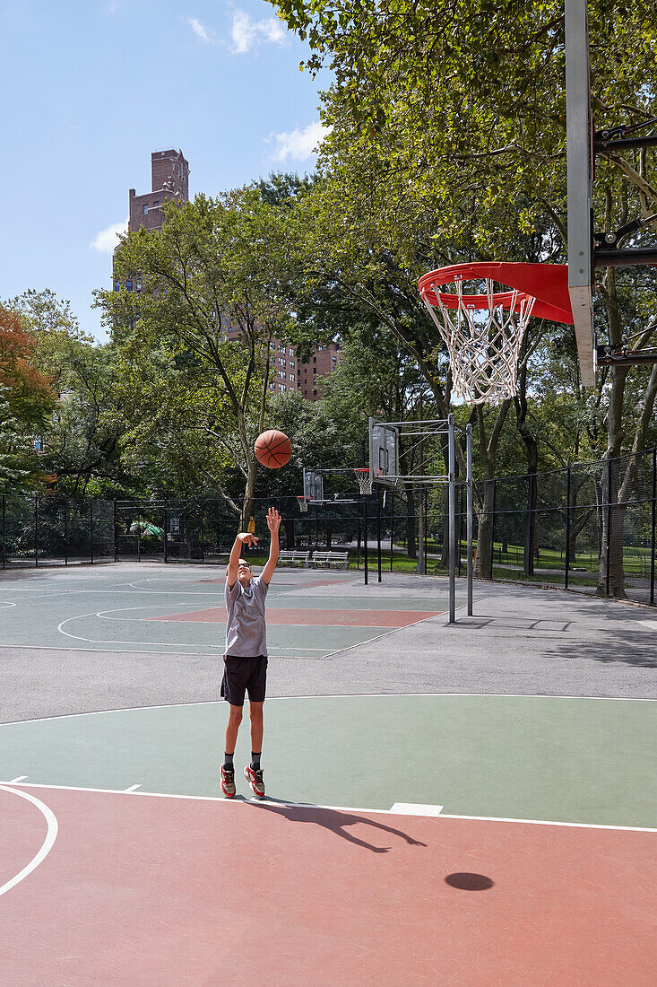 Boy (8-9) playing basketball in park