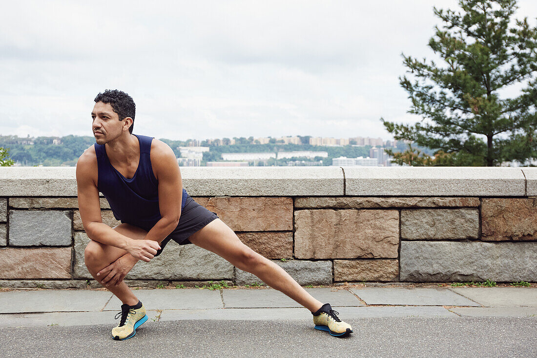 USA, New York, New York City, Man in sports clothing stretching outdoors