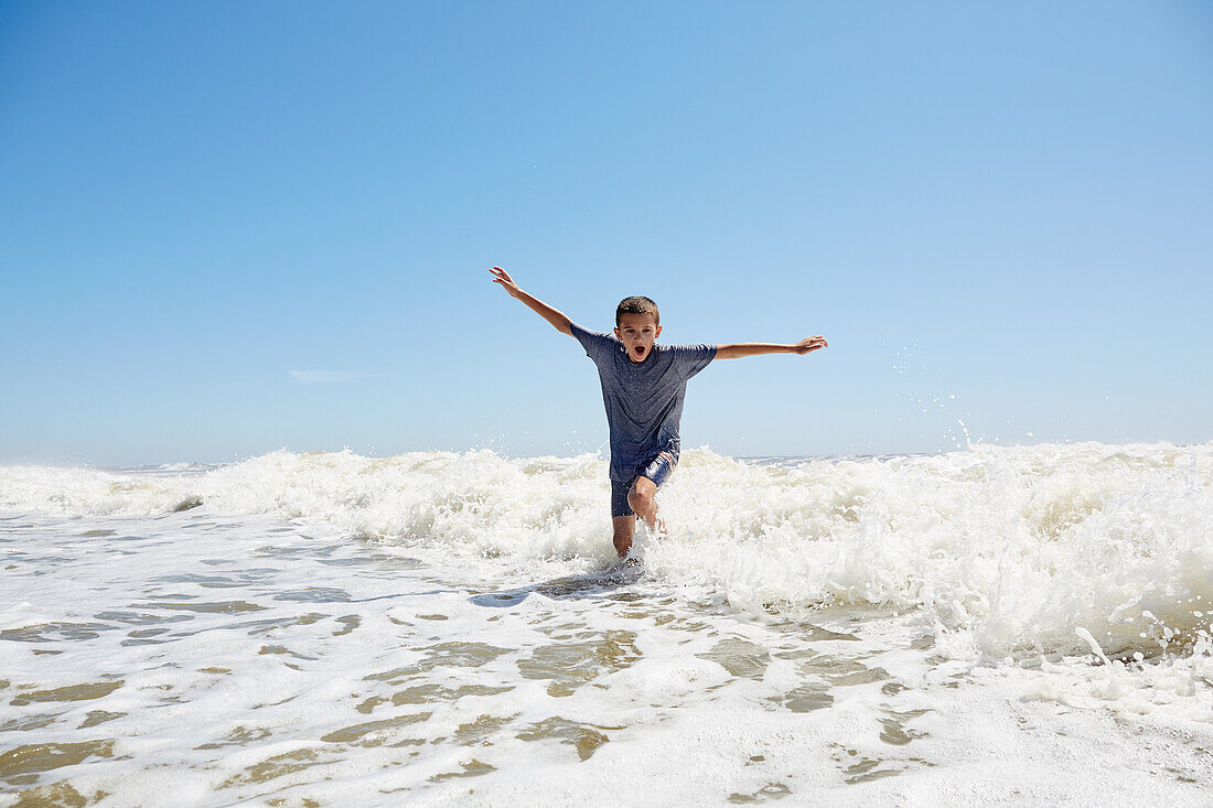 Boy (8-9) playing in sea waves