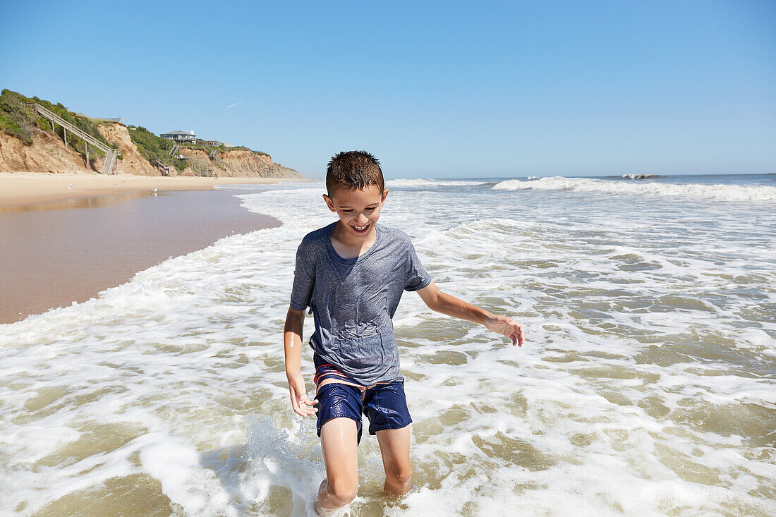 USA, New York, Montauk, Smiling boy (8-9) playing in sea waves