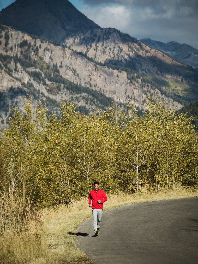 Vereinigte Staaten, Utah, American Fork, Mann joggt auf Bergstraße an sonnigem Tag