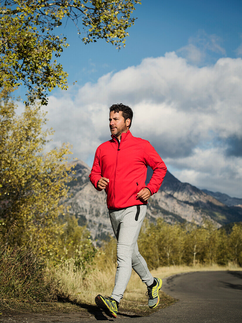 Vereinigte Staaten, Utah, American Fork, Mann joggt auf einer Bergstraße an einem sonnigen Tag