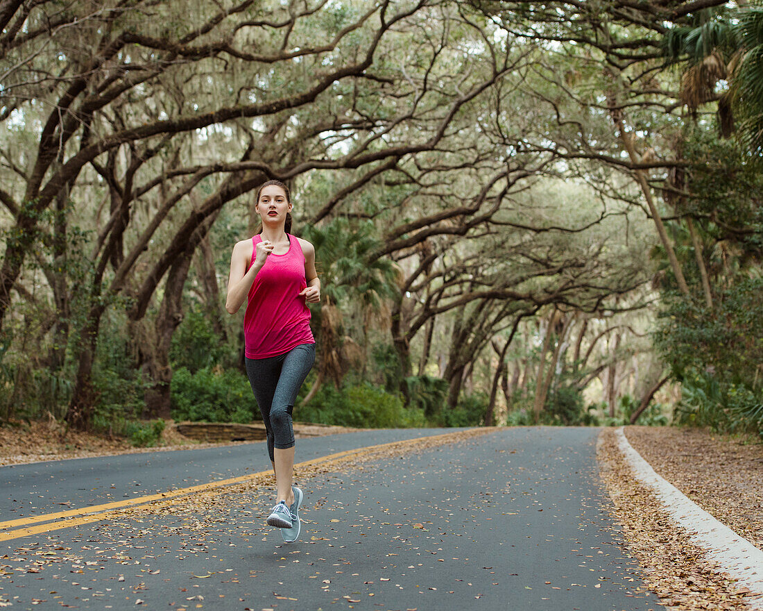 Woman jogging on treelined country road
