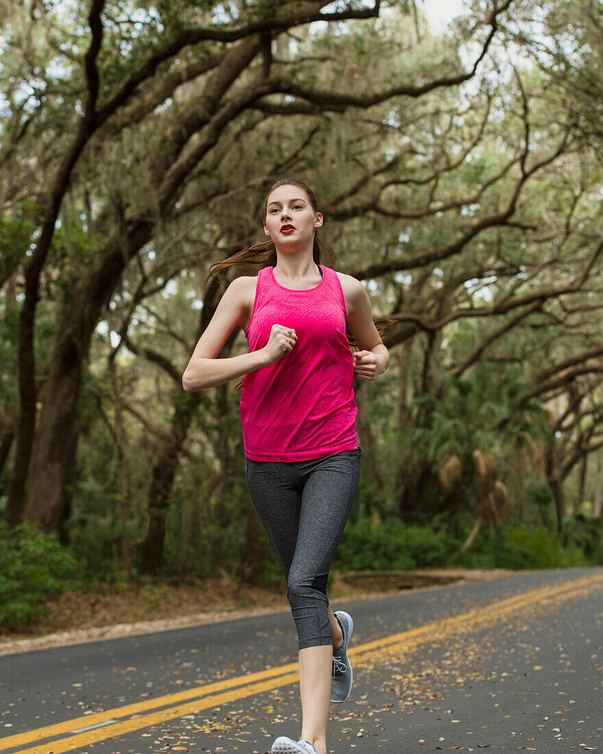 Woman jogging on treelined country road