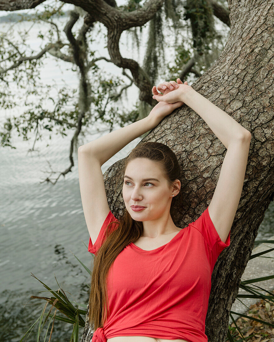 Smiling woman leaning against tree trunk