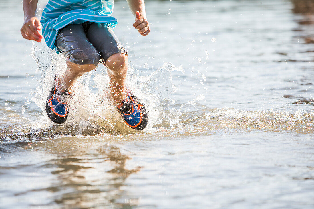 Low section of boy (8-9) jumping in lake