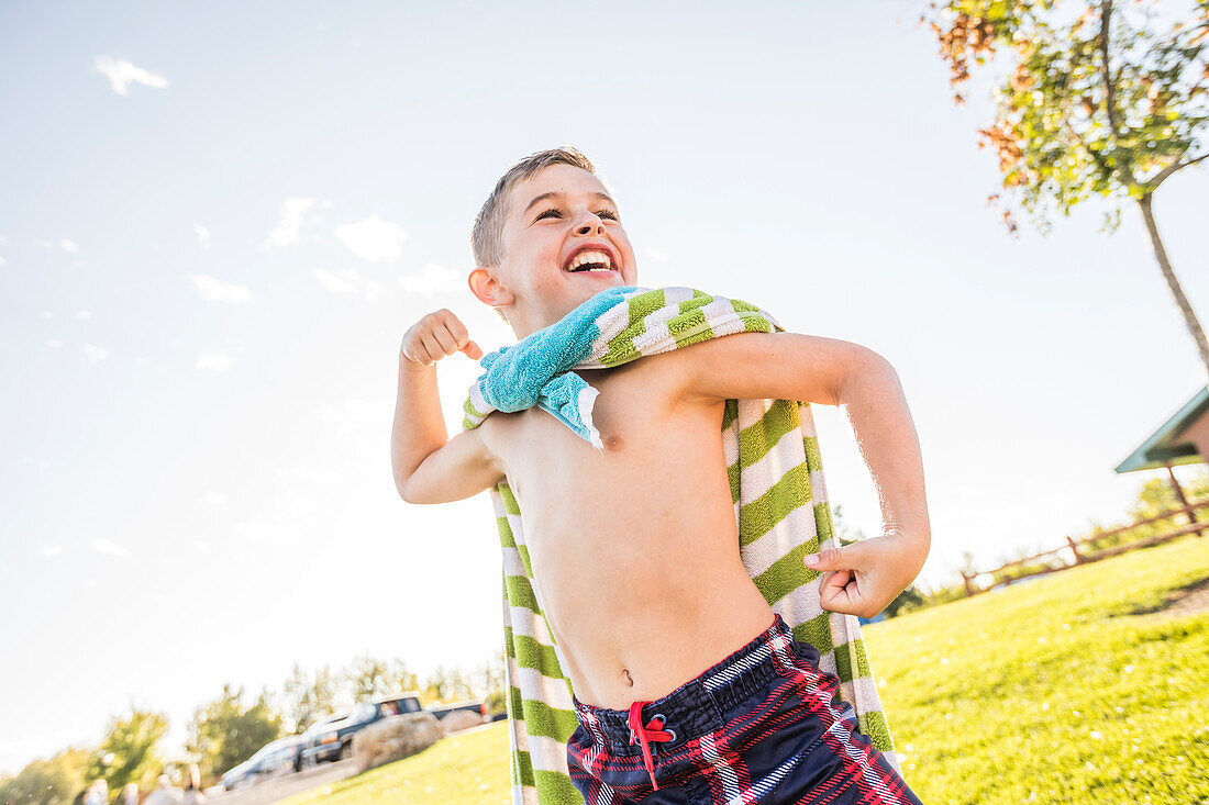 Junge ohne Hemd (8-9) lässt Muskeln im Garten spielen