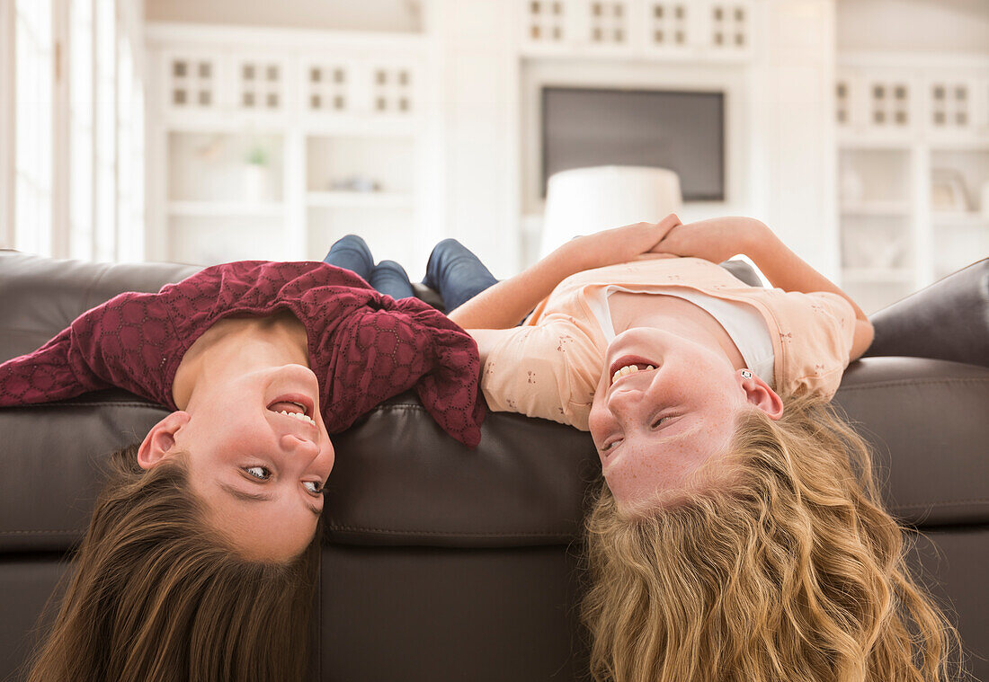 Sisters (10-11, 12-13) laughing on sofa
