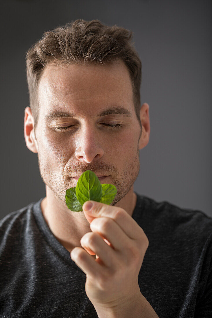 Studio shot of man smelling fresh mint leaves