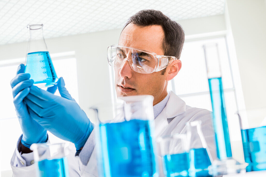 Wissenschaftlerin betrachtet blaue Flüssigkeit im Labor