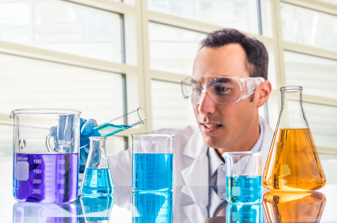 Wissenschaftler gießt blaue Flüssigkeit im Labor ein