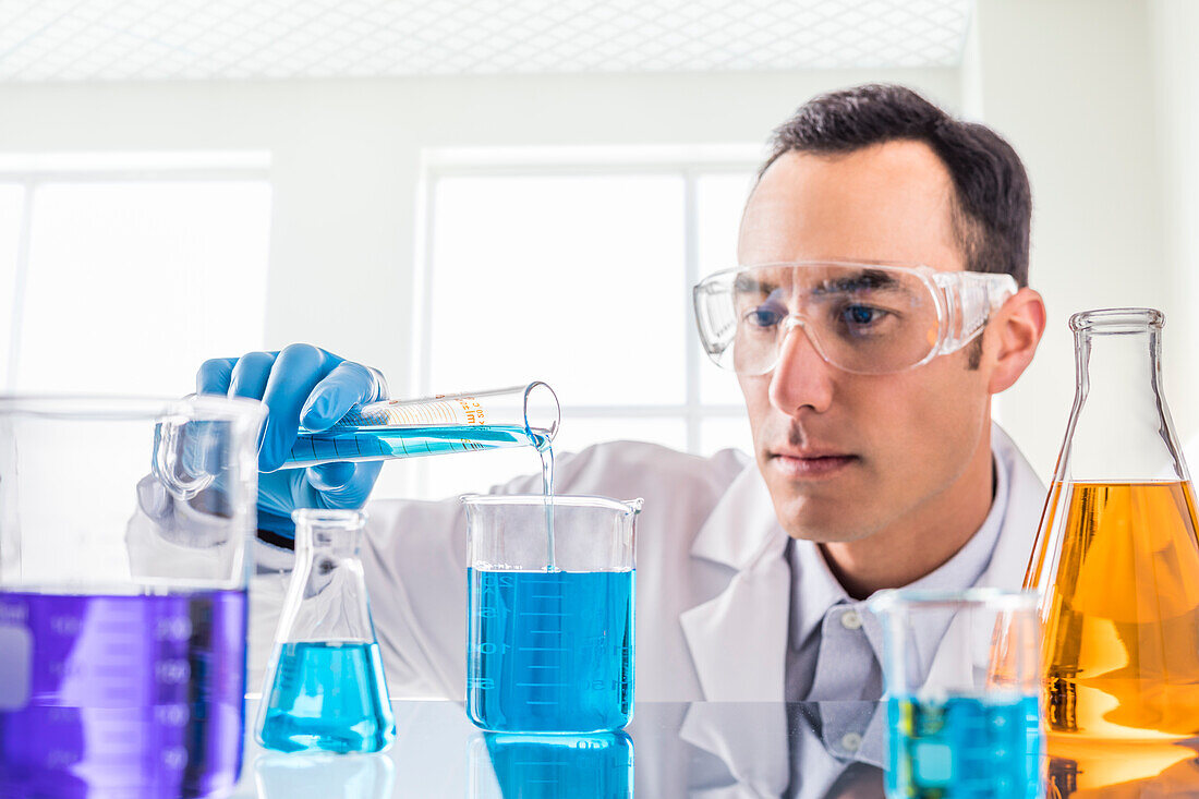 Wissenschaftler gießt blaue Flüssigkeit im Labor ein