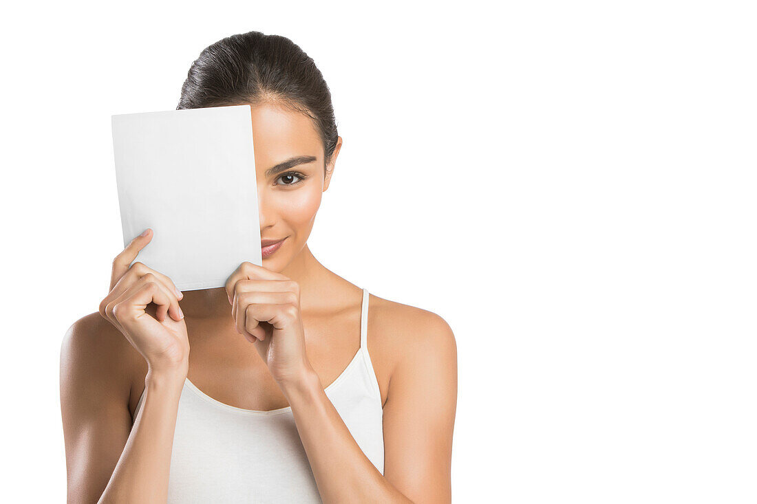 Porträt einer Frau, die sich ein Papier vor das Gesicht hält