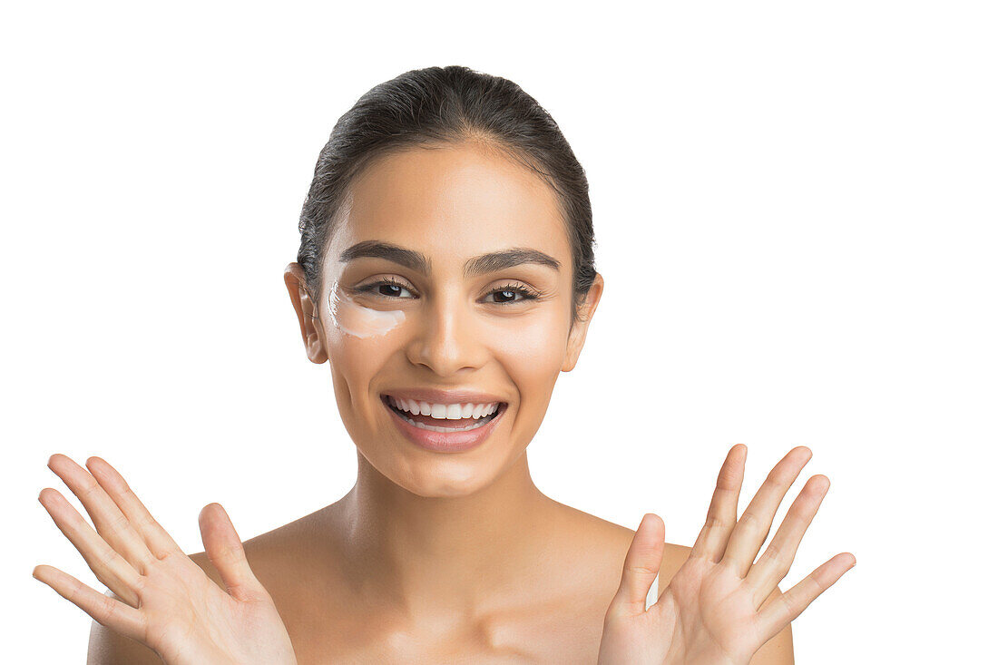 Portrait of smiling young woman applying face cream 