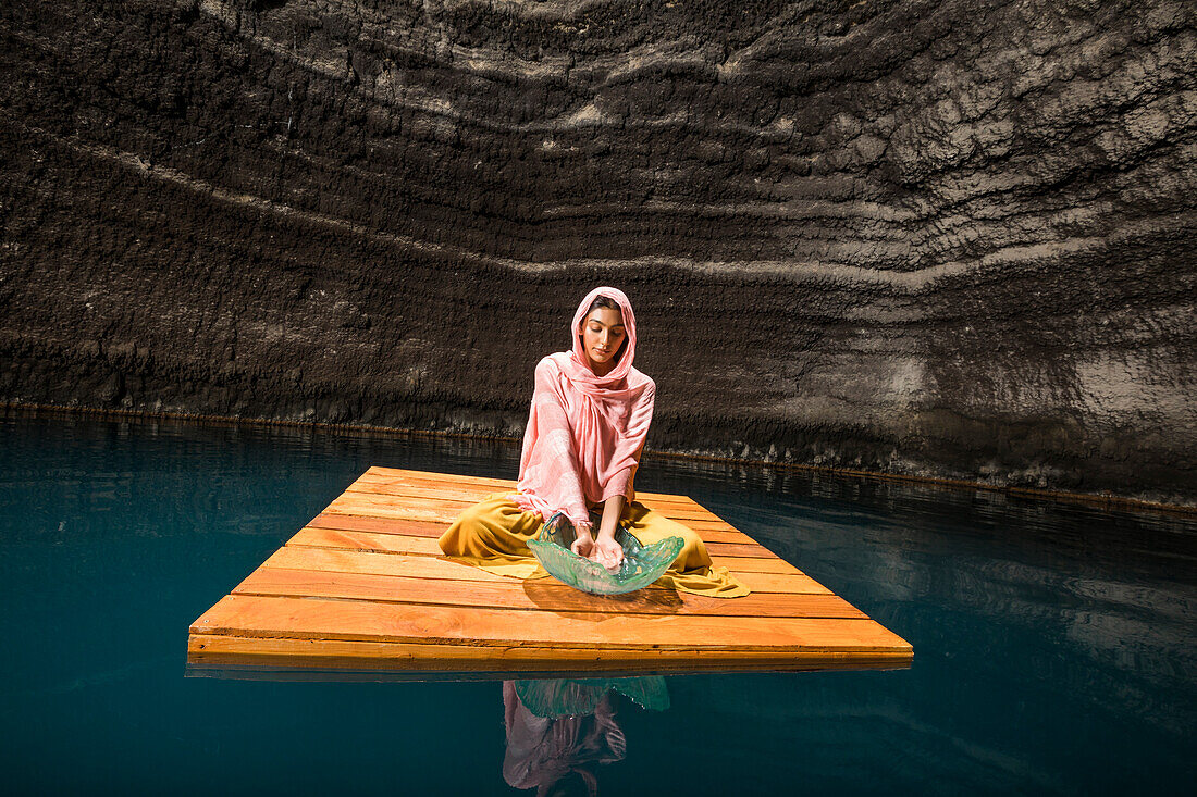 Woman sitting on wooden raft in cenote