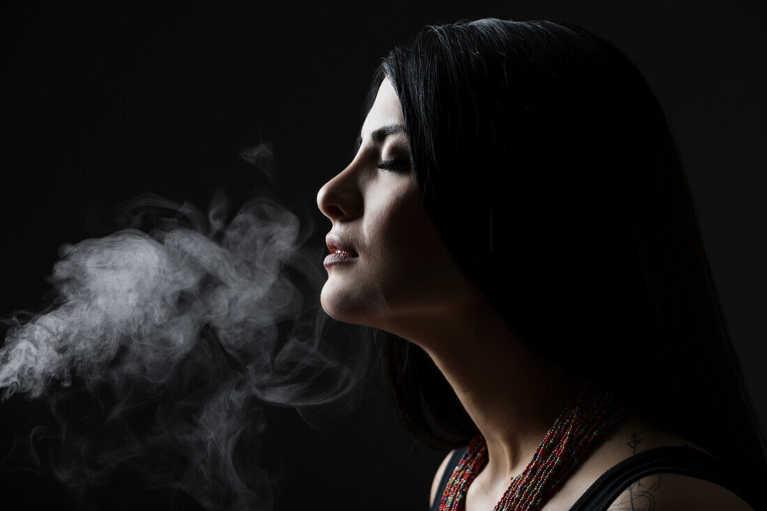 Profil einer Frau mit Rauch vor schwarzem Hintergrund