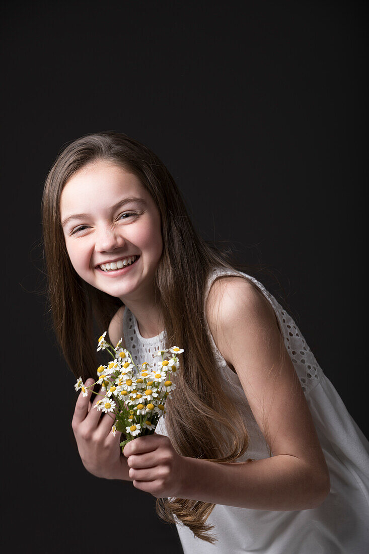 Studio portrait of smiling girl (10-11) holding bunch of wildflowers