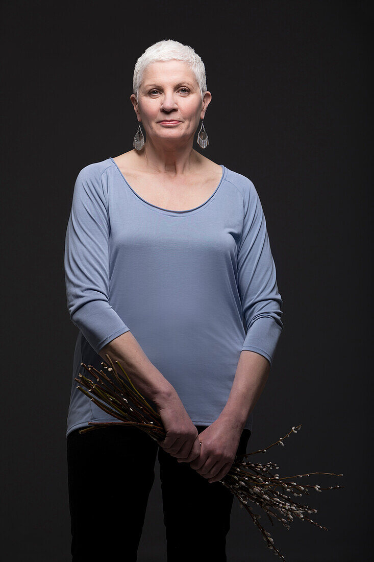 Studio-Portrait einer Frau mit einem Strauß blühender Zweige