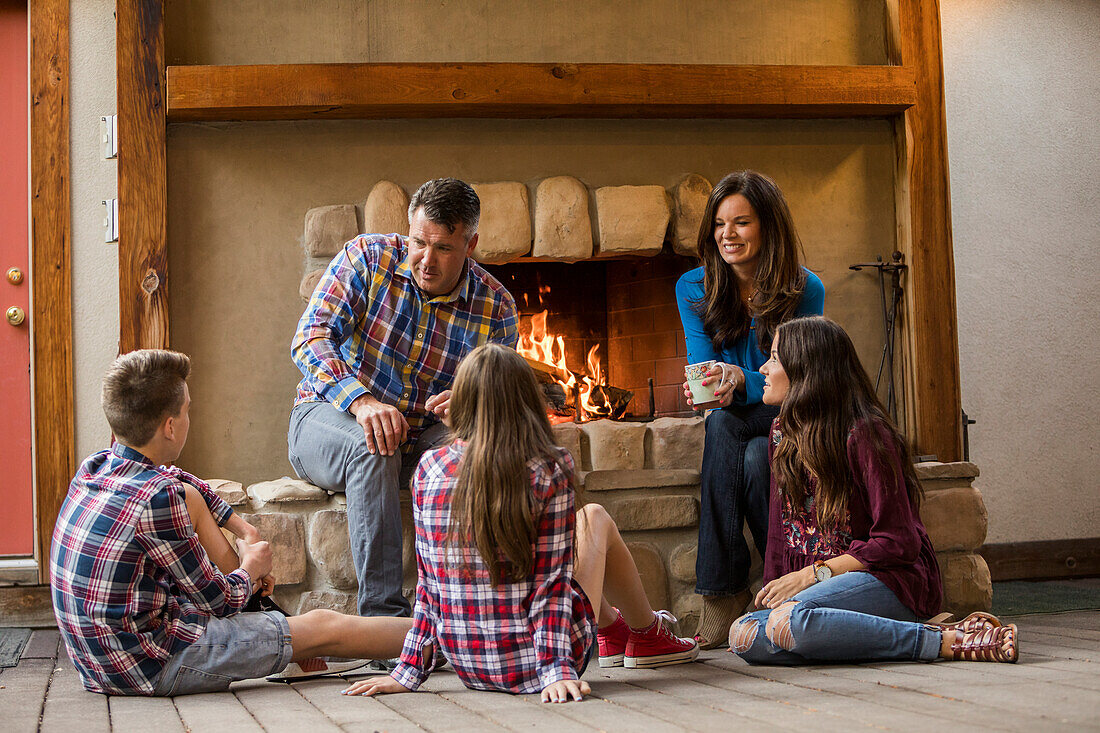 Family with children (10-11, 12-13, 16-17) sitting by fireplace