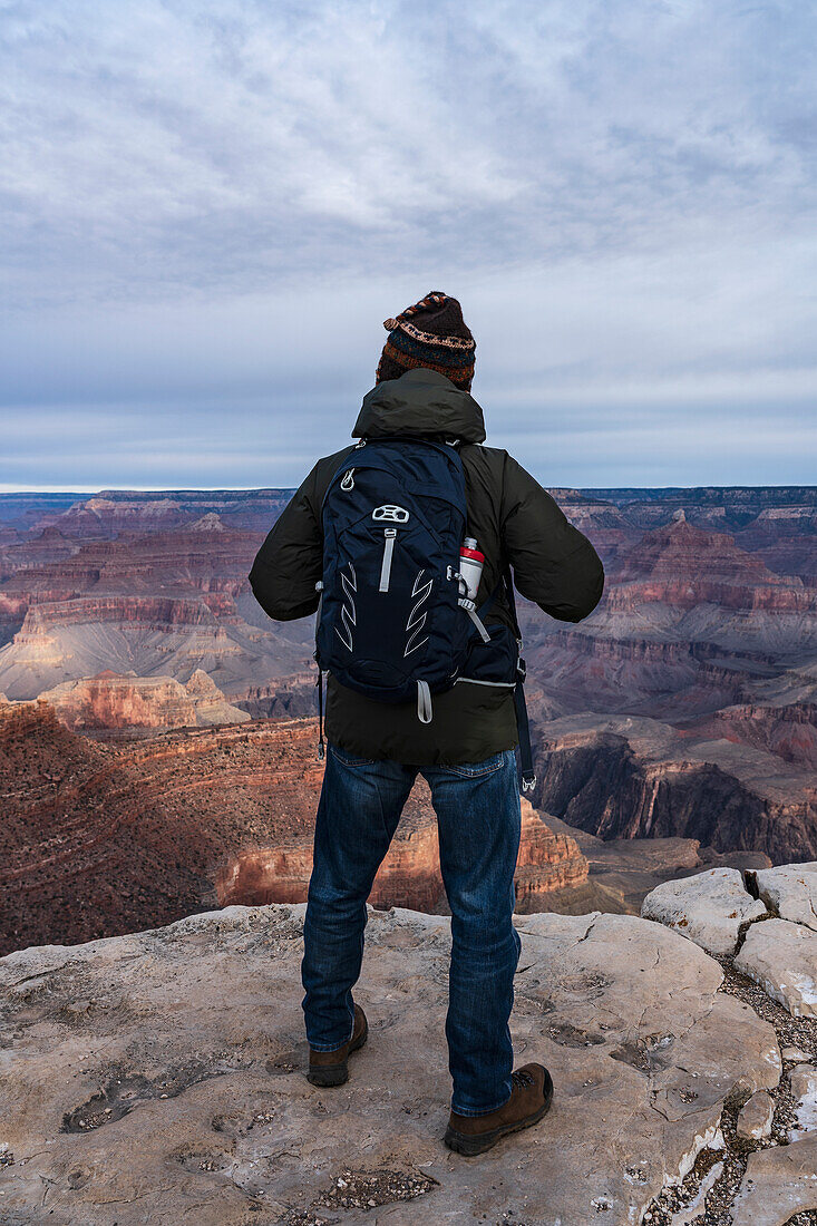 Vereinigte Staaten, Arizona, Grand Canyon National Park, South Rim, Älterer männlicher Wanderer steht am Rande des Grand Canyon bei Sonnenaufgang 