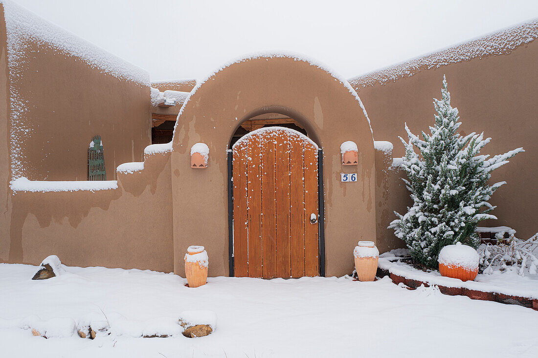 United States, New Mexico, Santa Fe, Autumn snow at front of Pueblo style home 