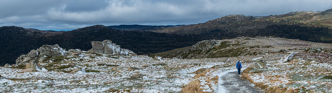 Australien, Neusüdwales, Snowy Mountains National Park, Frau wandert auf verschneitem Weg am Charlotte Pass im Kosciuszko National Park