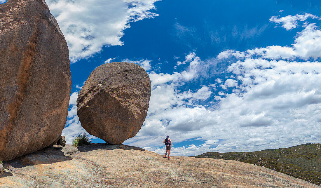 Australien, Queensland, Girraween-Nationalpark, Frau steht bei einer Wanderung in der Wildnis neben einem großen Felsen