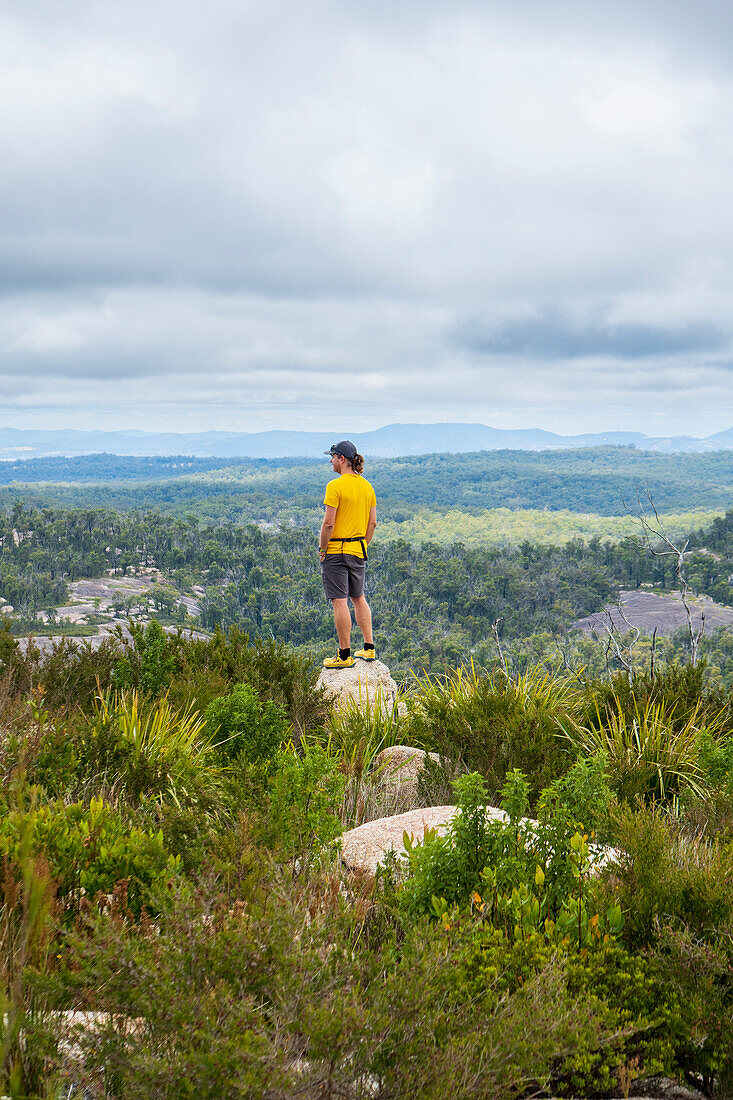 Australien, New South Wales, Bald Rock National Park, Mann steht auf einem Felsen und schaut sich um