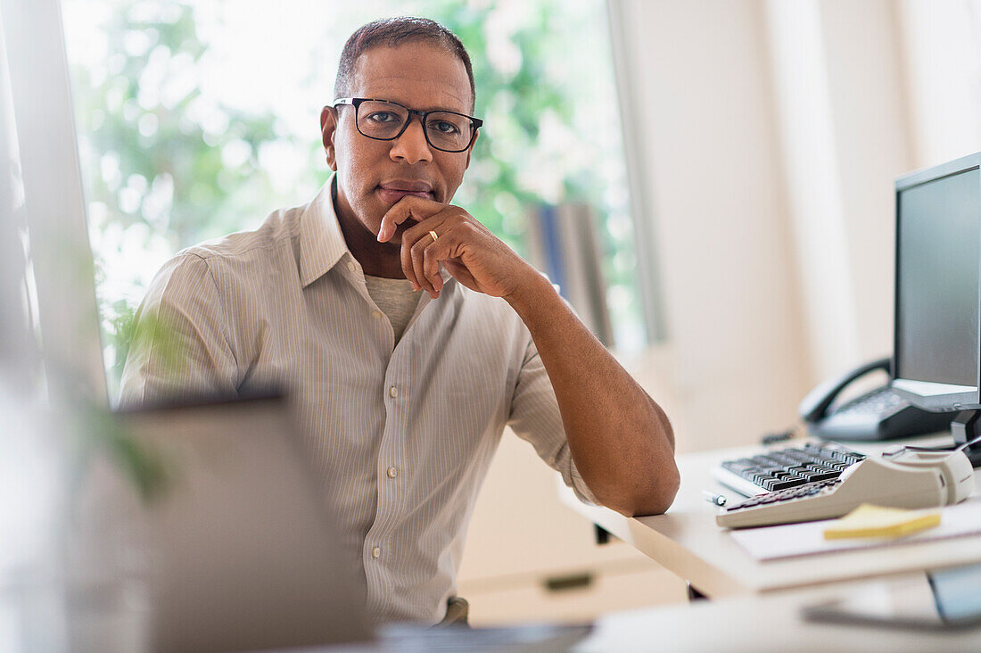 Porträt eines lächelnden reifen Mannes bei der Arbeit im Büro zu Hause