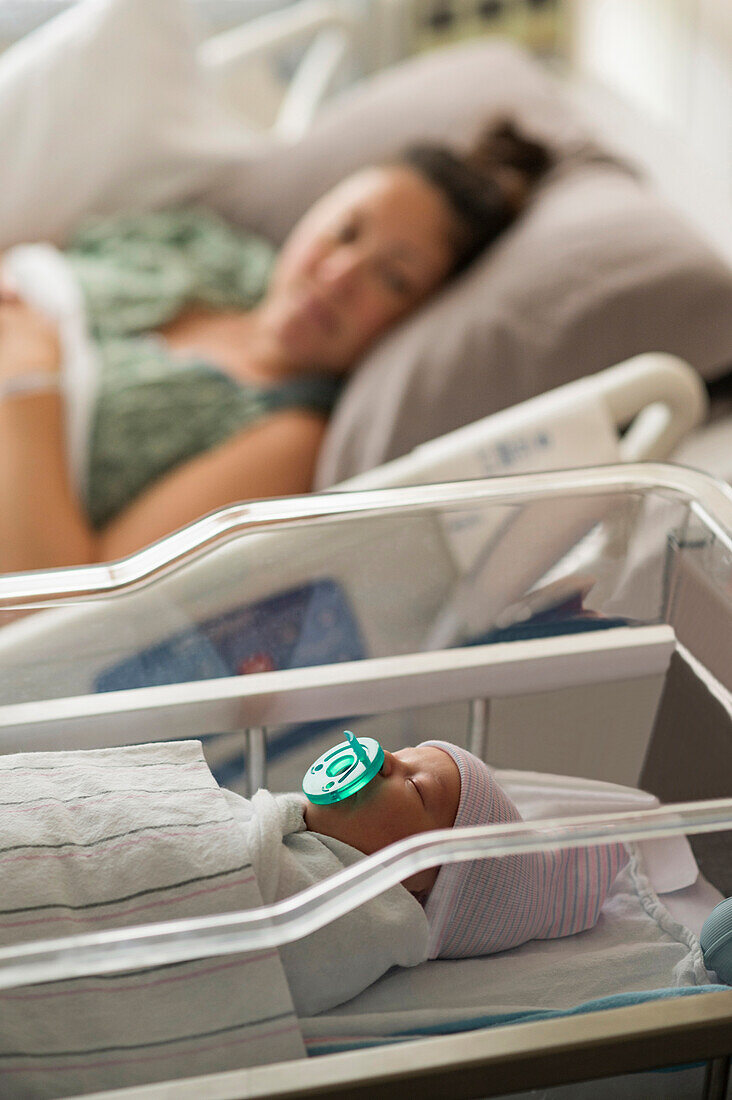 Mutter liegend mit neugeborenem Mädchen (0-1 Monate) im Krankenhaus